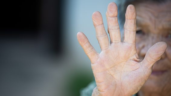 close up picture of old woman’s hand showing anti symbol
