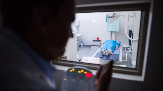 Doctor using x-ray unit control panel on patient in hospital