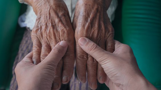 Young woman holding an elderly woman’s hand.